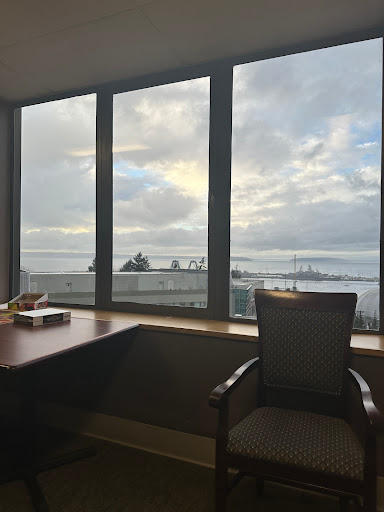 A serene office space featuring a large window with a view of the sky and water.