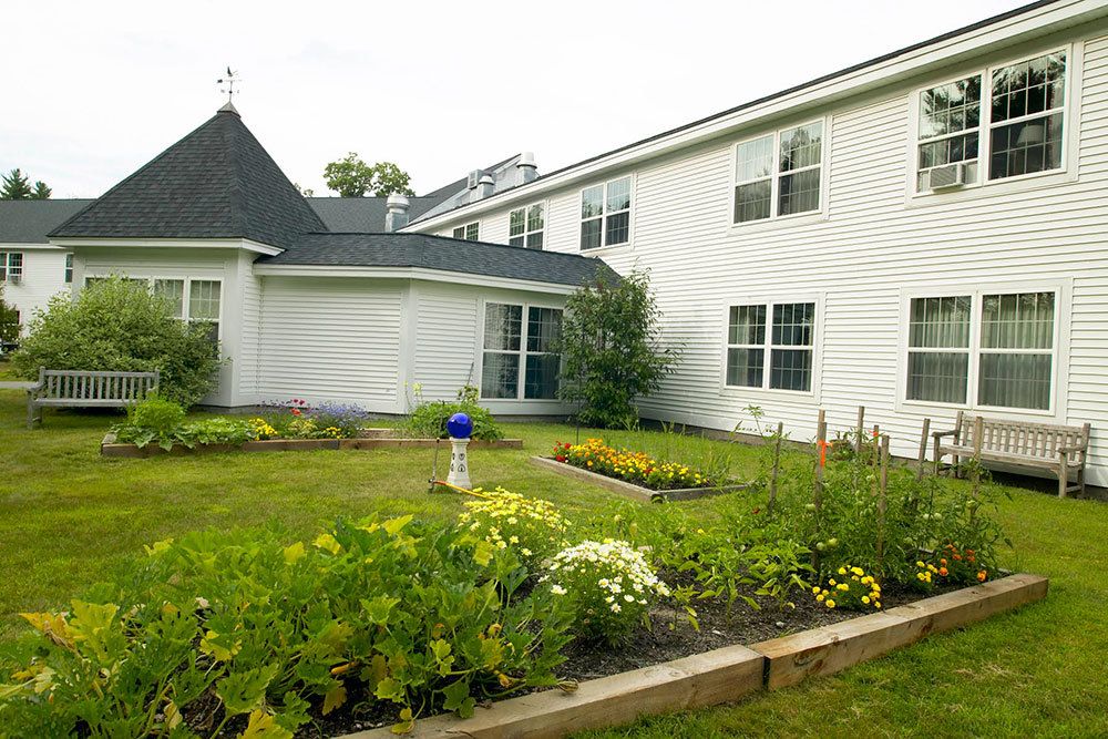 A white residential building with a beautifully maintained garden in the foreground.