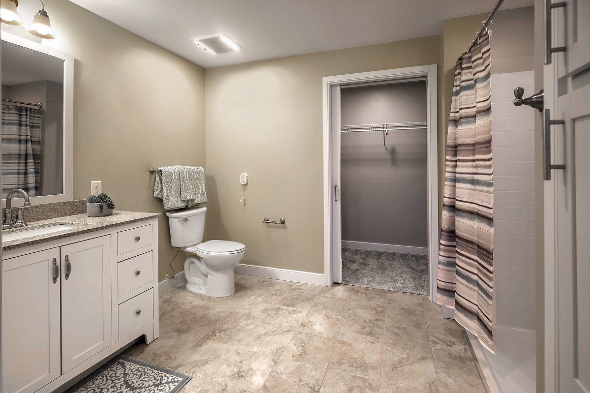 A spacious bathroom with a toilet, sink, and shower area.