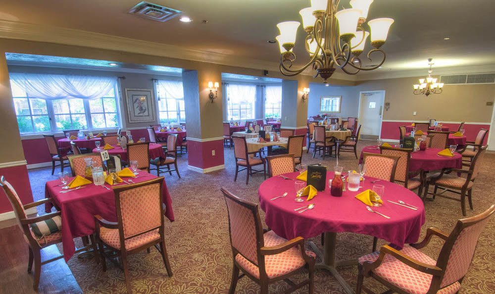 A cozy dining area with elegantly set tables and a chandelier overhead.