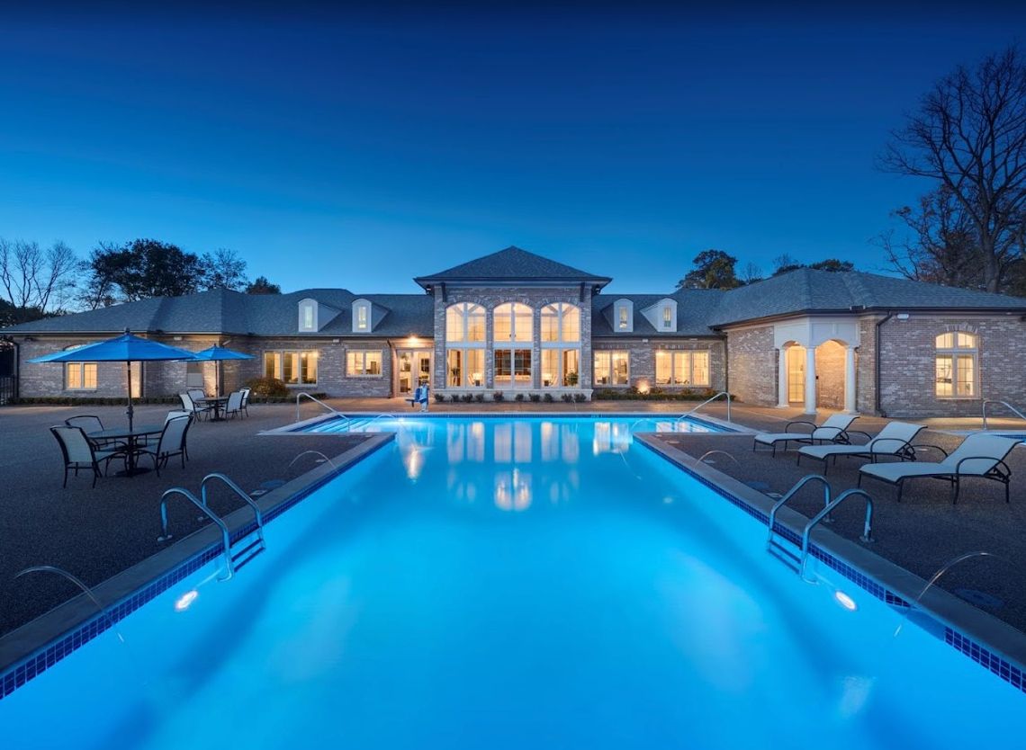 A luxurious mansion with a glowing swimming pool at night.