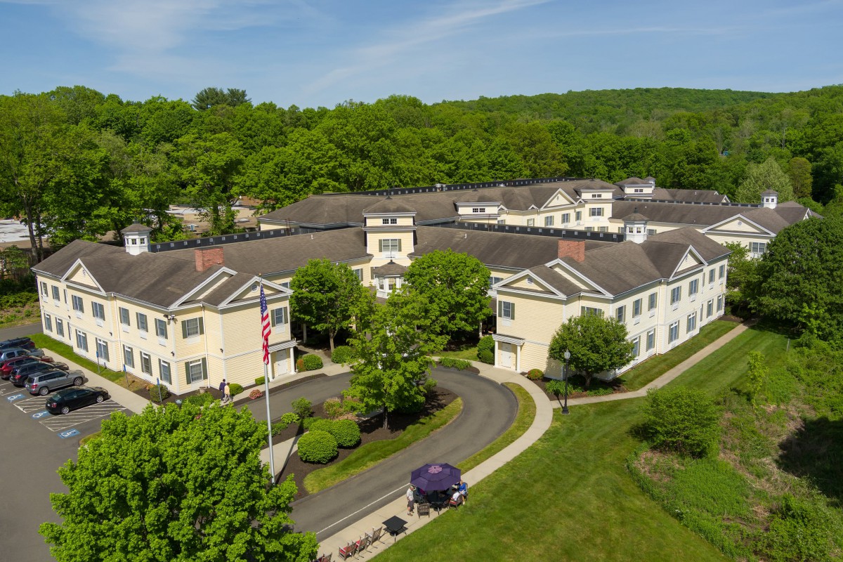 Aerial view of a large building surrounded by greenery and roads.