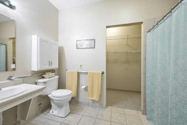 A modern bathroom with a toilet, shower, and neatly arranged towels.