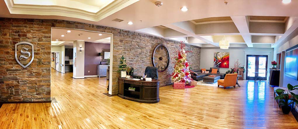A warmly decorated office reception area with a brick wall, wooden flooring, and a festive Christmas tree.