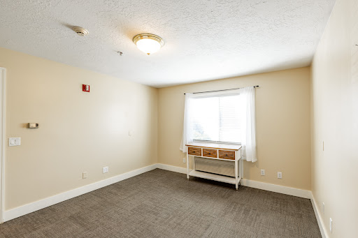 A spacious, empty room featuring a window and minimal furniture.