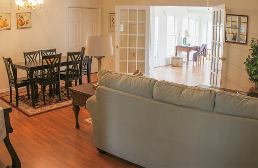 A cozy living room featuring a comfortable sofa, a dining area with chairs, and plenty of natural light.