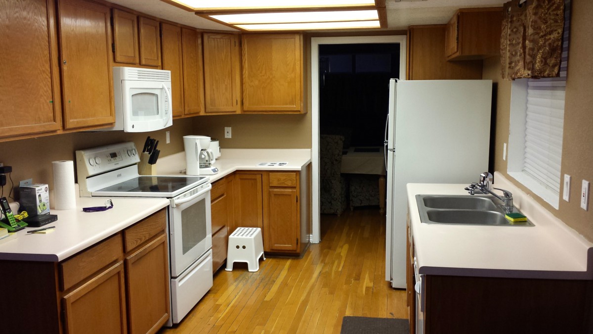 A clean kitchen with wooden cabinets, white countertops, and modern appliances.