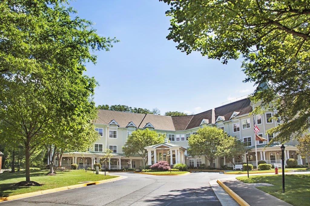 A residential building with a landscaped driveway and trees on a sunny day.