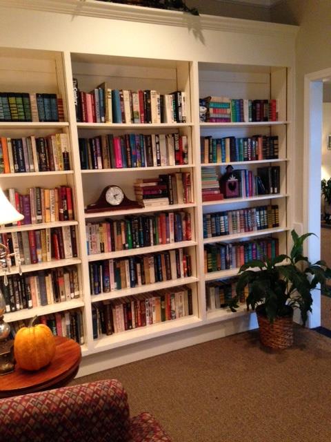 A cozy living room with a large bookshelf filled with books and a plant nearby.