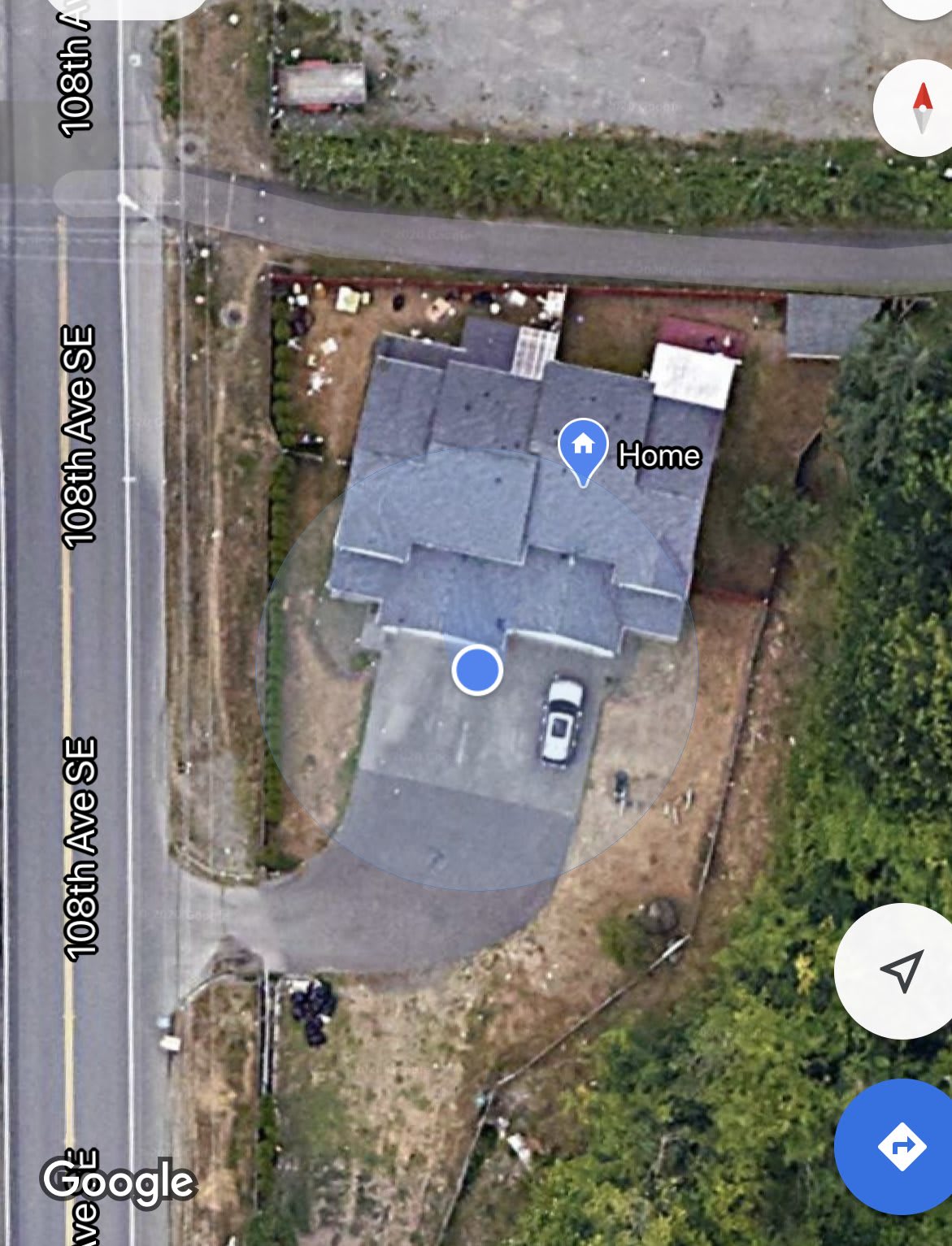 Aerial view of a house with a driveway and surrounding trees.