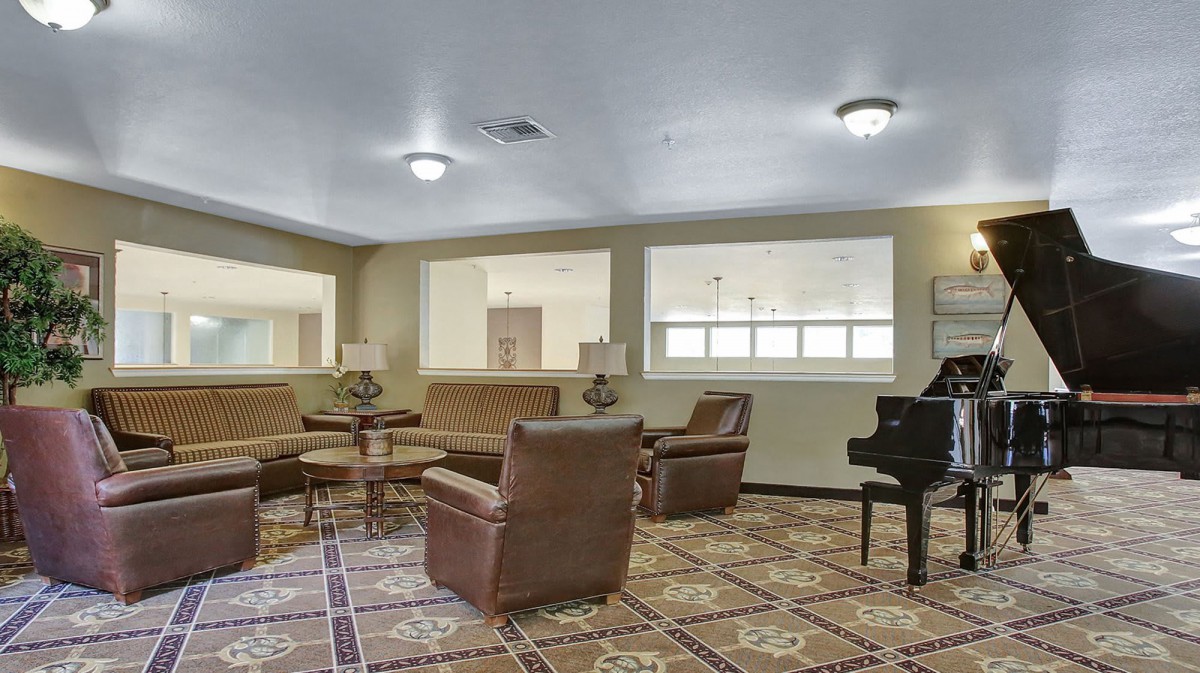 A cozy living room with armchairs, a coffee table, and a piano.