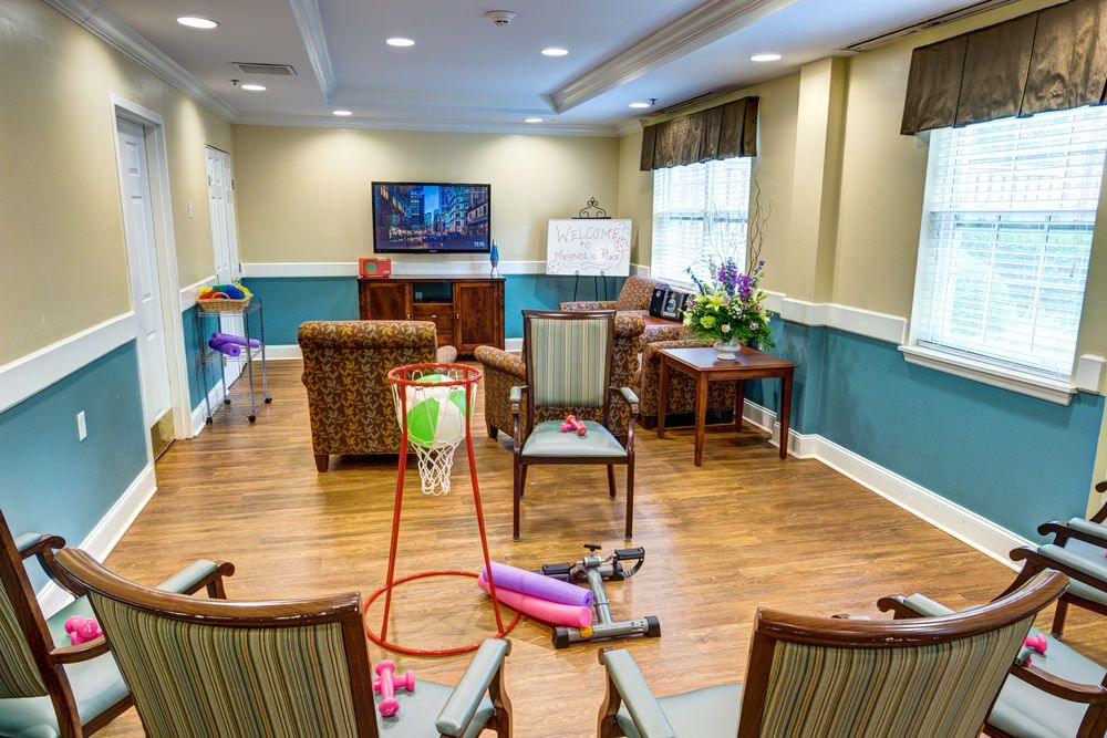 A cozy living room setup with chairs facing a TV, exercise equipment, and a vase of flowers.