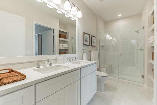 A modern bathroom featuring a double vanity with sinks, a large shower, and neutral-toned decor.