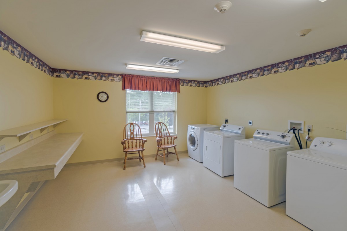 A bright laundry room with washing machines, dryers, and a folding table.
