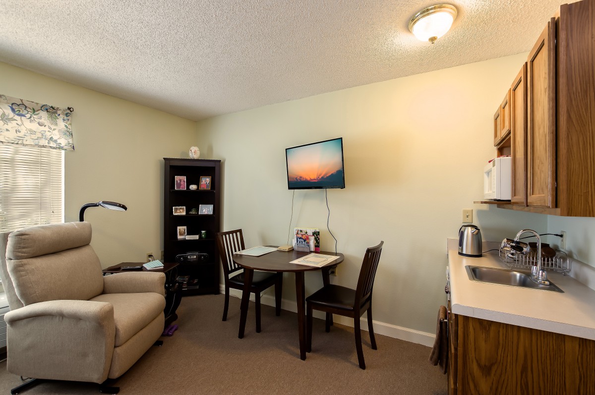 A cozy office space with a table, chairs, and a wall-mounted television.