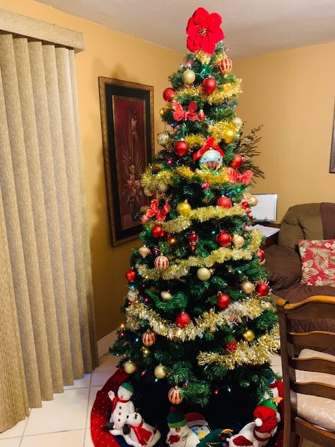 A beautifully decorated Christmas tree adorned with ornaments and tinsel, creating a festive indoor atmosphere.