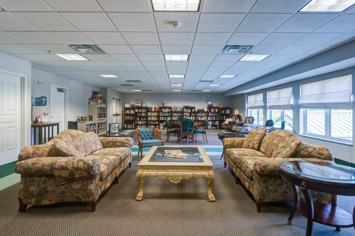 A cozy library reading area with sofas and shelves filled with books.