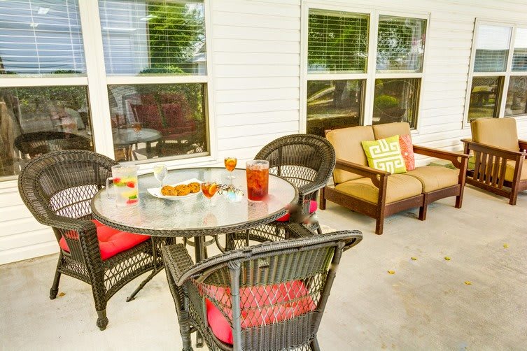 An inviting patio area with a round table, chairs, and a cozy sofa adorned with cushions.