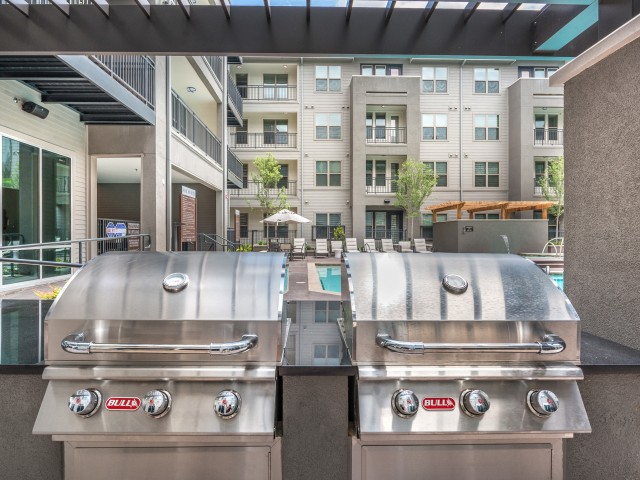 Outdoor grilling area in a modern apartment complex.