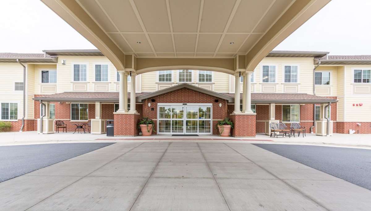 Covered entrance of a building with columns and glass doors.