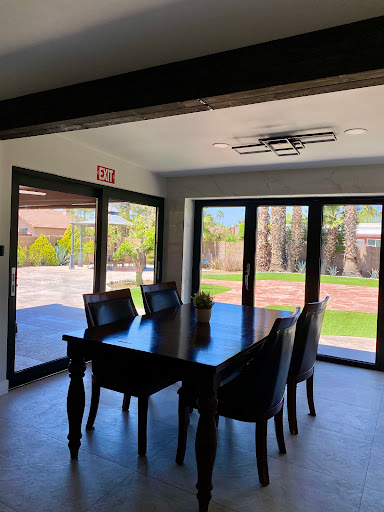 A modern dining room featuring a wooden table and chairs with large windows offering an outdoor view.
