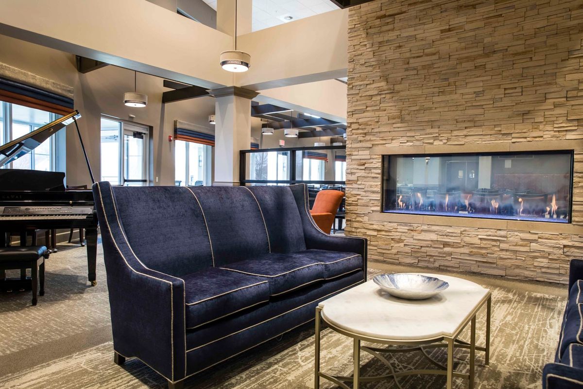 A modern lounge area featuring a dark sofa, stone fireplace, and a stylish coffee table.