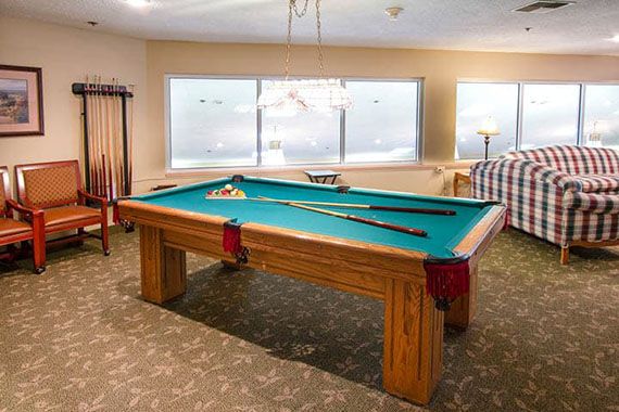 A pool table in a spacious game room with cue sticks and billiard balls arranged for play.