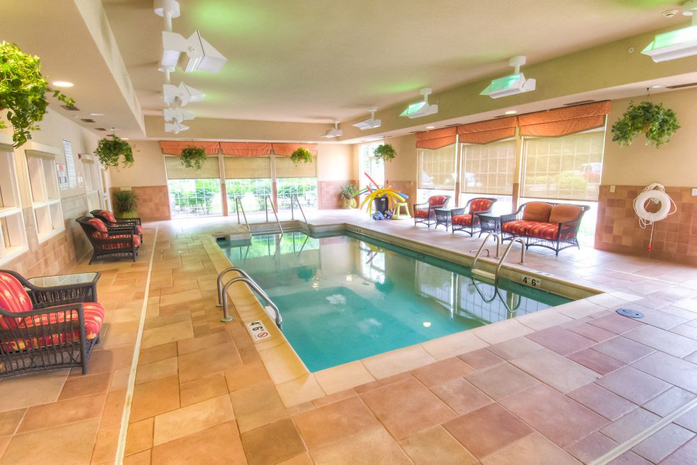 A serene indoor swimming pool with lounge chairs and natural lighting, perfect for relaxation.