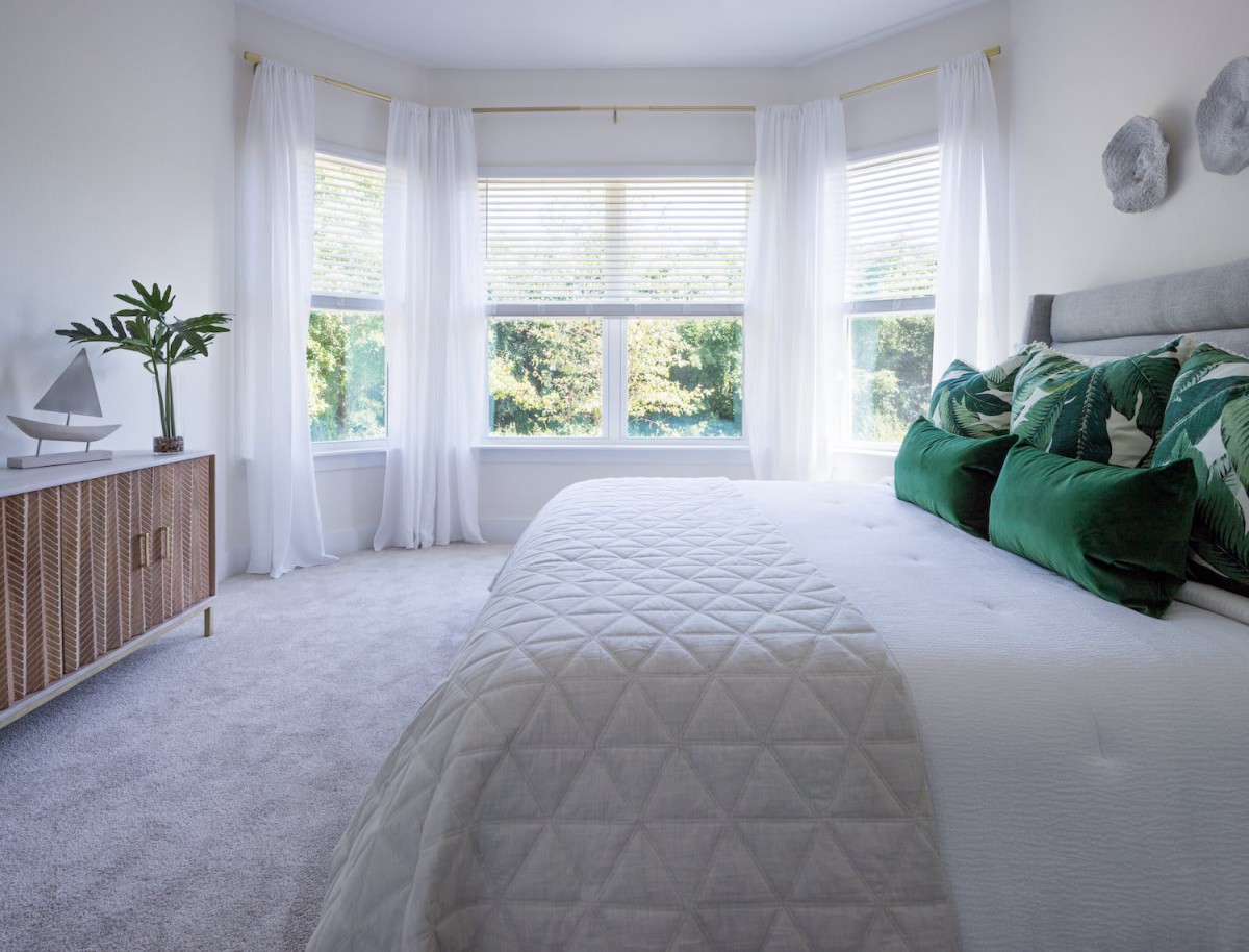 A bright and modern bedroom with green accents and ample natural light.