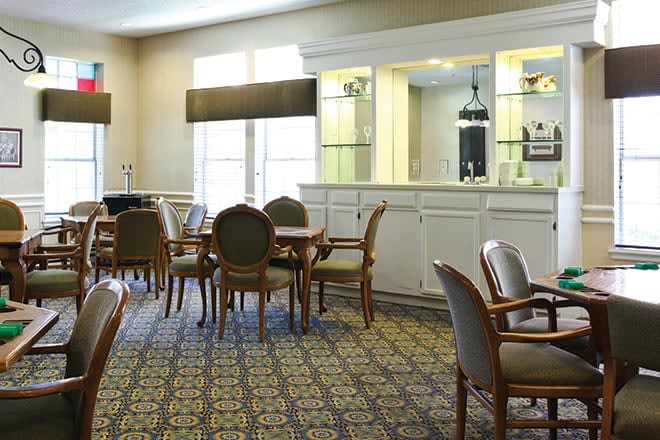 A well-lit dining area featuring several tables and chairs with decorative carpeting.