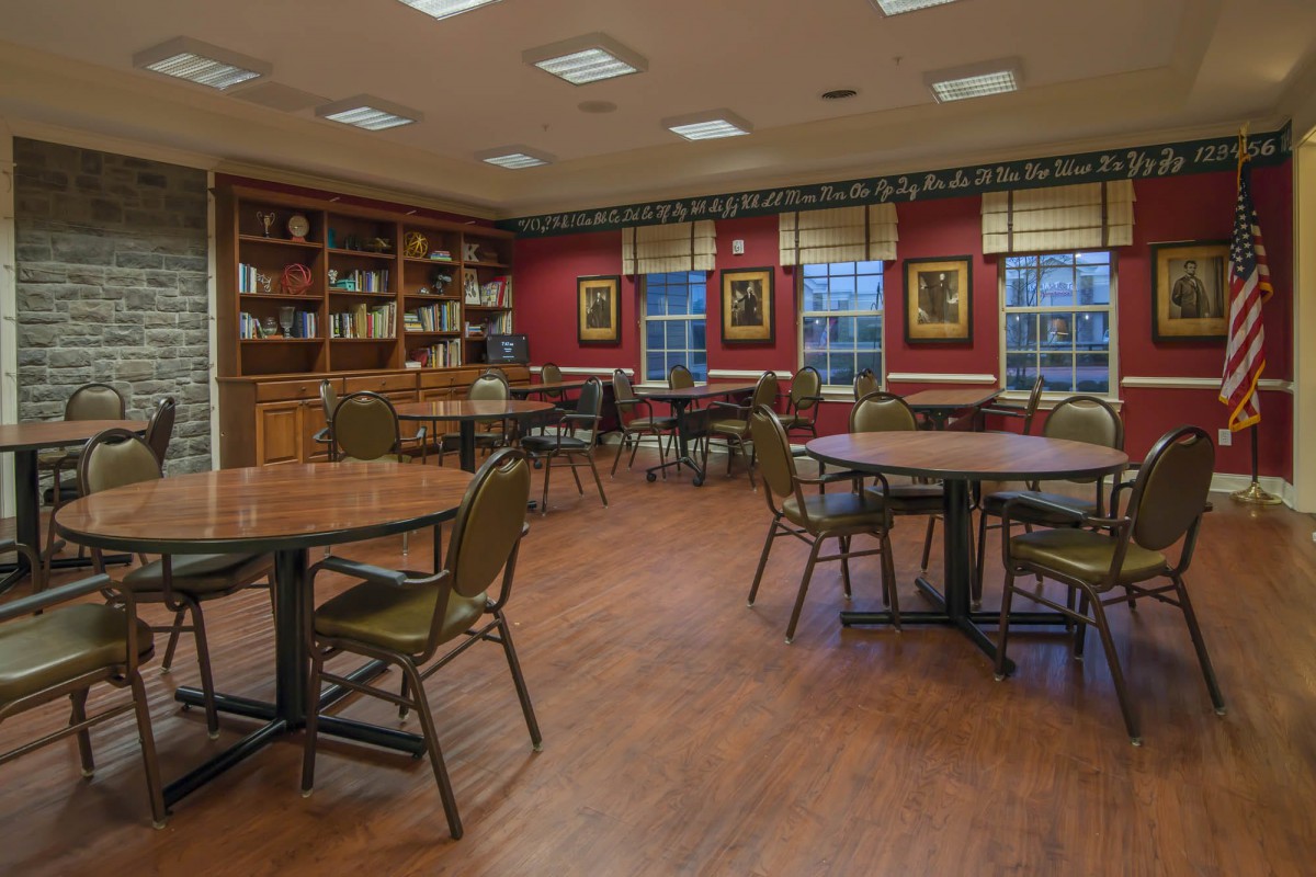 A cozy library reading room with tables and chairs surrounded by bookshelves.
