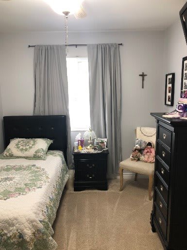 A neatly organized bedroom with a bed, dresser, and chair adorned with decorative items.