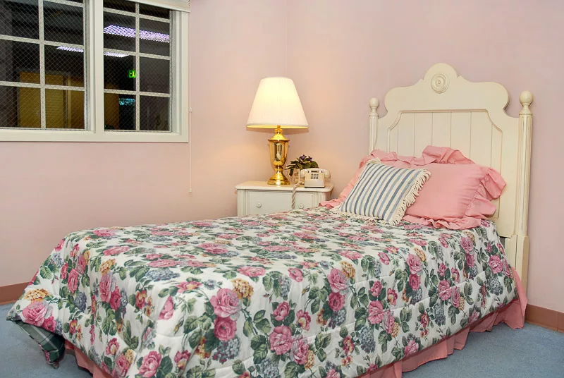 A cozy bedroom with floral bedding and pink walls.