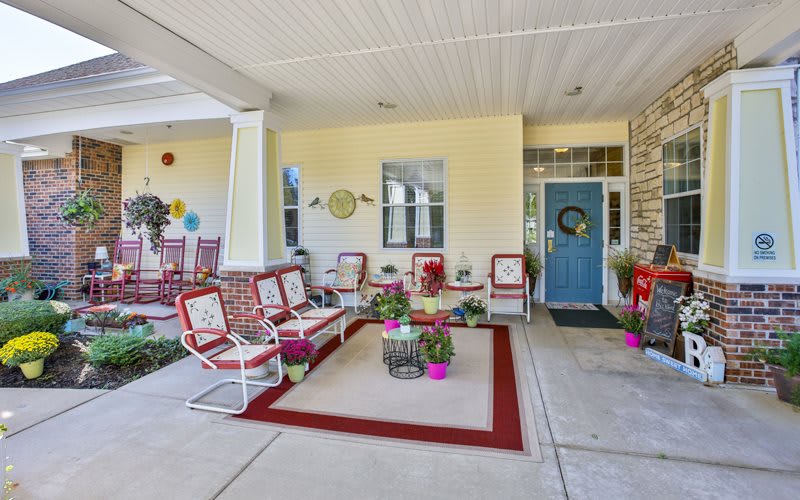 A cozy patio area with red and white furniture, potted plants, and decorative accents.