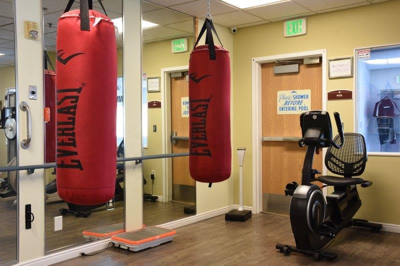 A small gym with a punching bag, exercise bike, and mirrors.