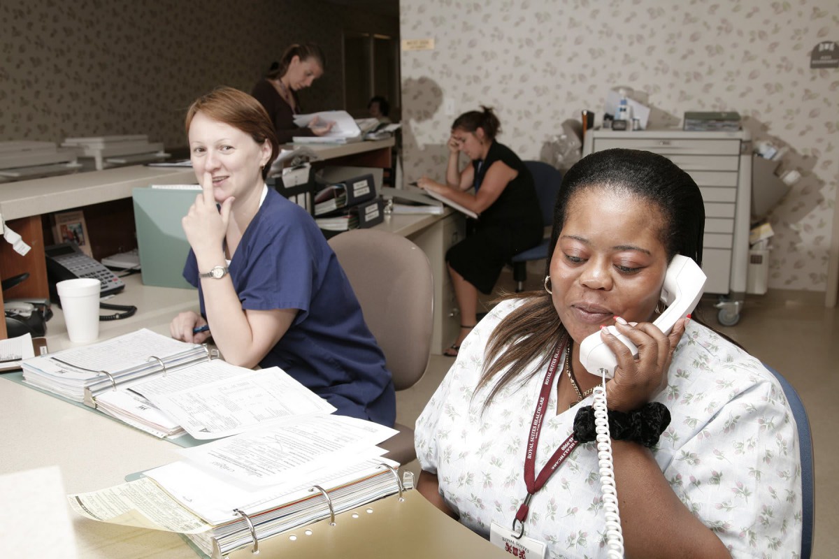 Office workers handling tasks at their desks, with one on the phone.