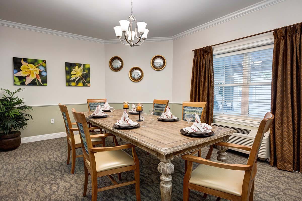 A cozy dining room with a wooden table set for a meal, surrounded by chairs and adorned with a chandelier.