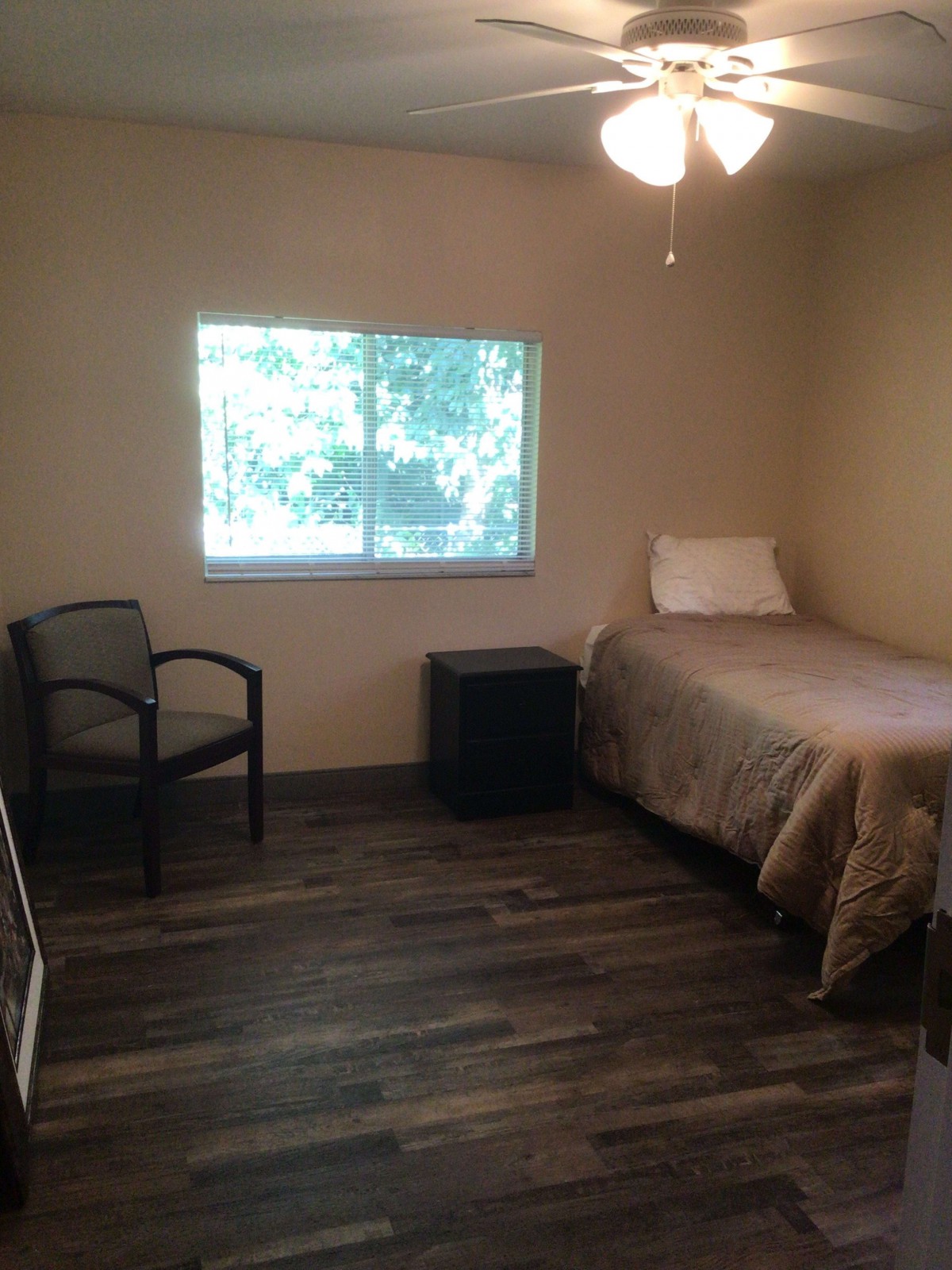 A minimalist bedroom with a single bed, chair, and window.