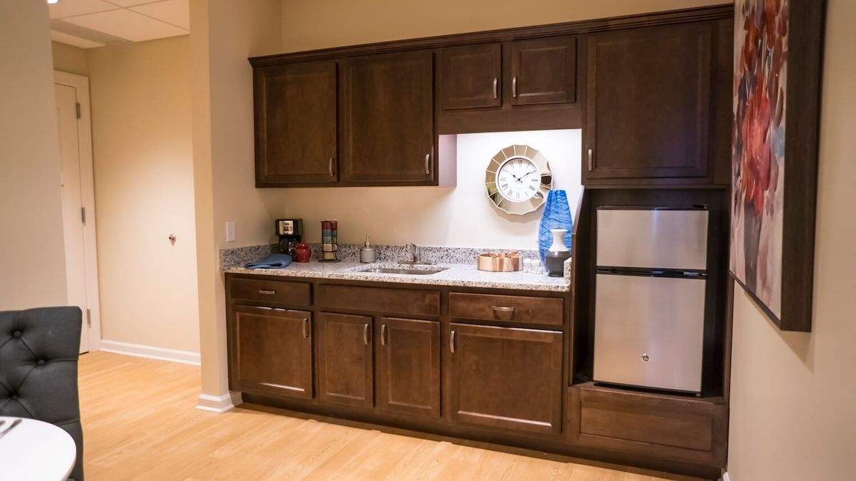 A modern kitchen with dark wooden cabinets and a small refrigerator.