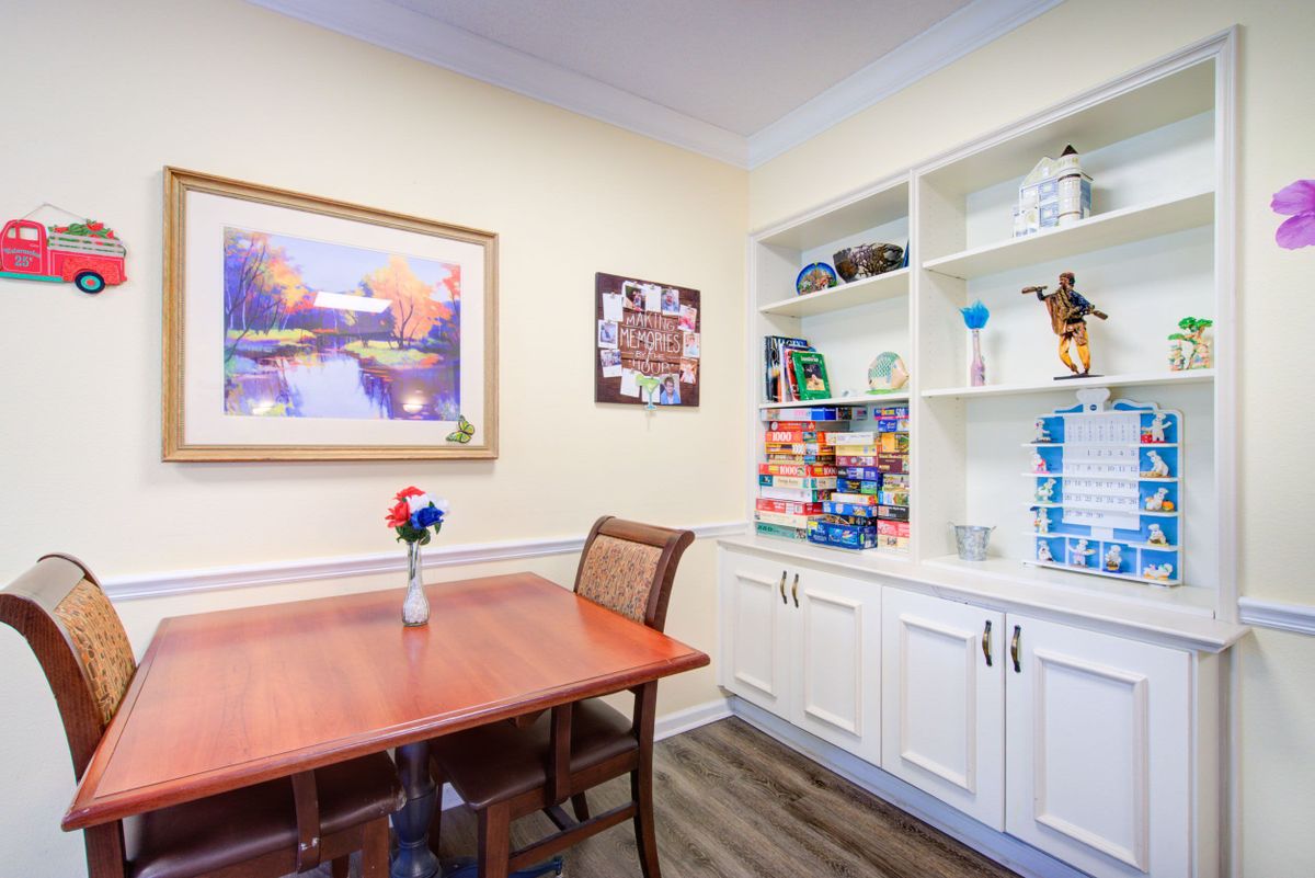 A cozy dining room featuring a wooden table, chairs, built-in shelves, and decorative items.