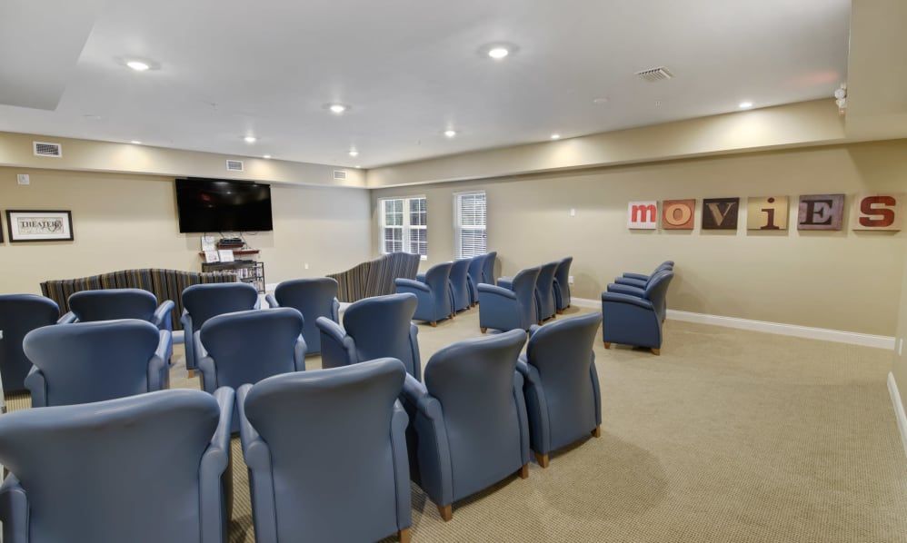 A well-arranged conference room with blue chairs facing a large television screen.