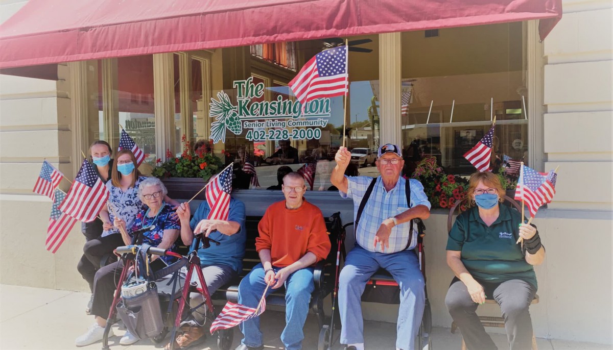 A group of elderly individuals sitting outdoors, holding American flags in a display of patriotism.