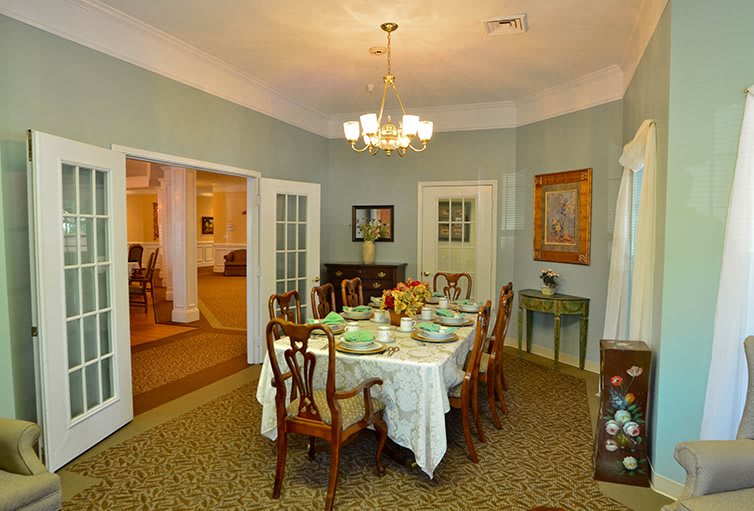 A traditional dining room with an elegantly set table and a chandelier overhead.