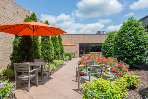 A serene outdoor garden space featuring comfortable seating and vibrant flowers under bright orange umbrellas.