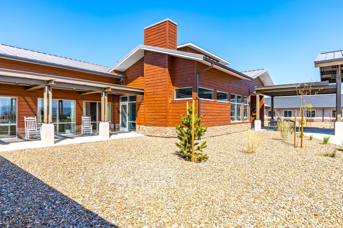 A modern house with wood siding and gravel landscaping on a sunny day.
