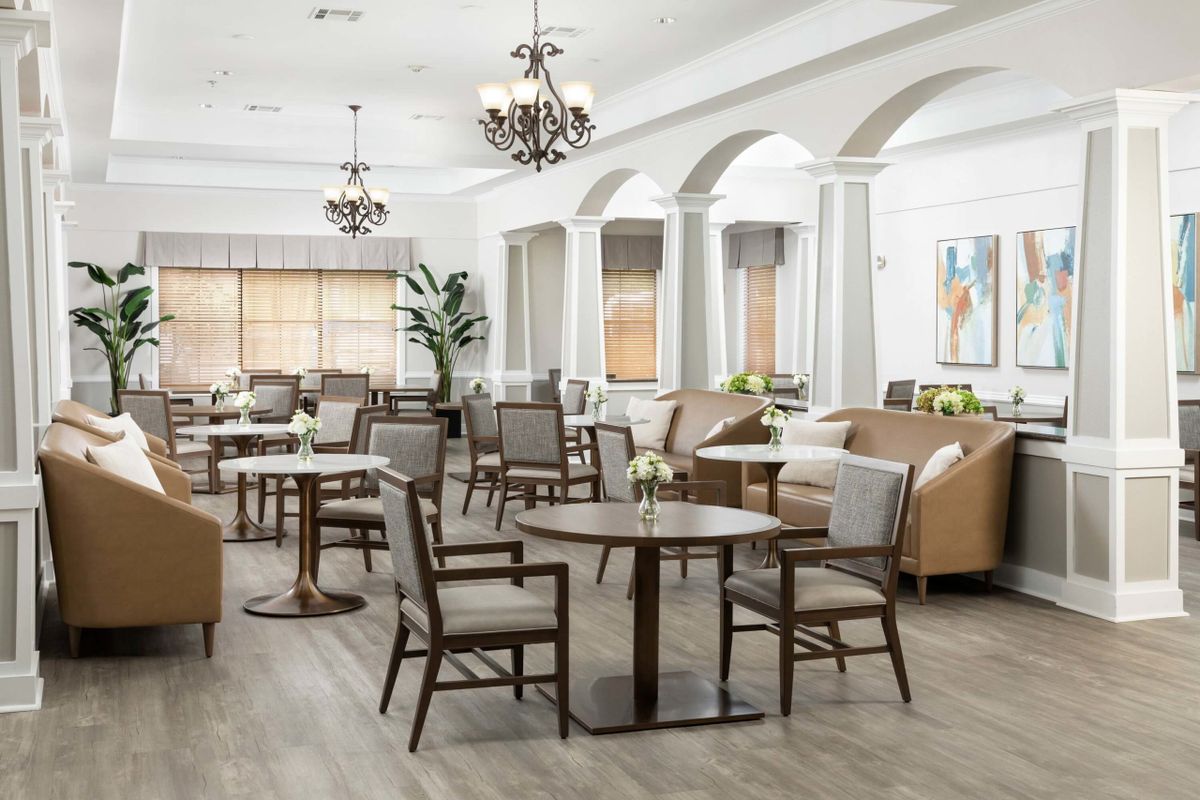 A modern dining area with tables and chairs, featuring elegant chandeliers and a bright atmosphere.