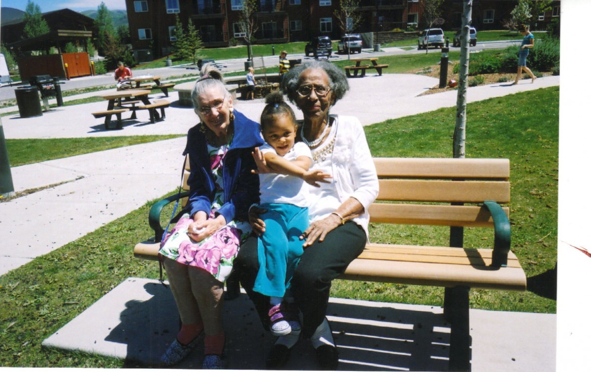 Three generations enjoying a sunny day in the park, sitting together on a bench.