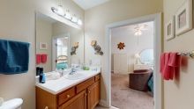 A bathroom with a large mirror above the sink, well-lit by overhead lights.