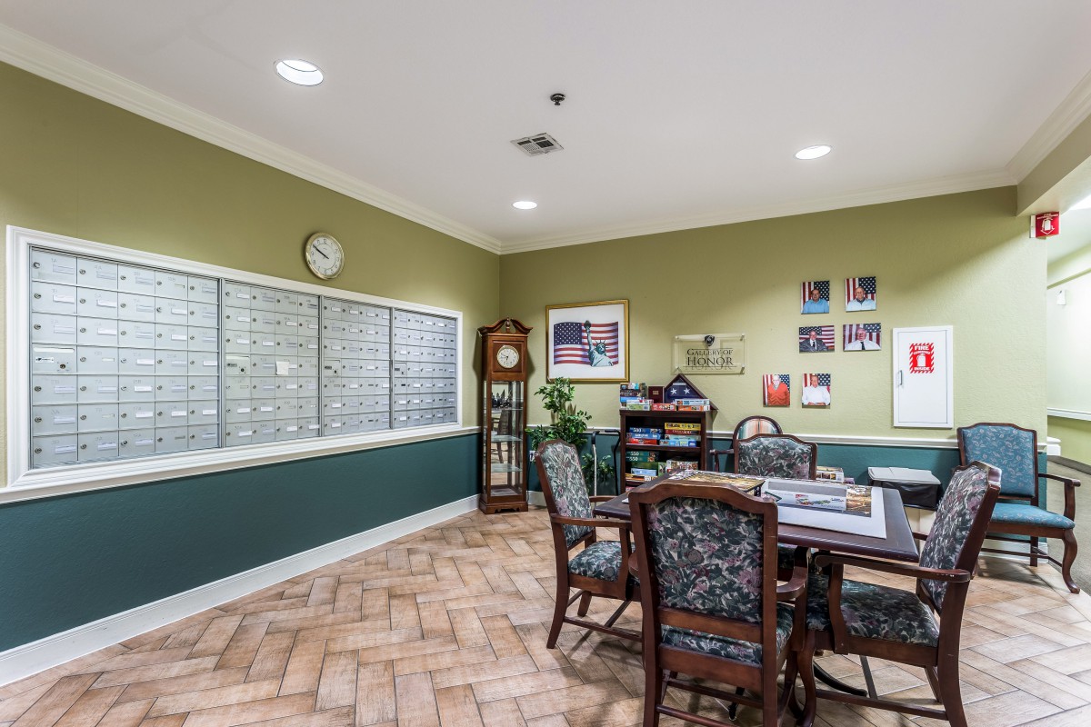A cozy and neatly arranged room with seating, a table, wall decorations, and mailboxes.