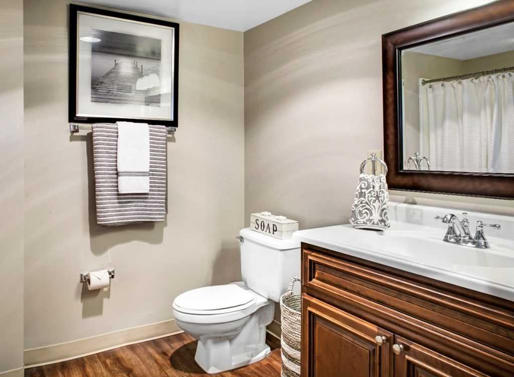 A neatly organized bathroom with a toilet, sink, and mirror.